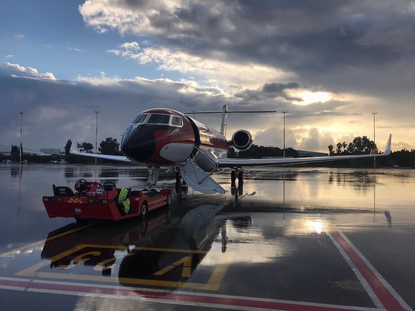 Business jet at dawn reflected on the wet apron